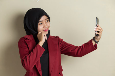 Happy Asian woman in hijab with mobile phone making selfie.の写真素材