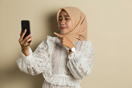 happy young asian muslim woman using mobile phoneの写真素材
