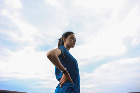 Portrait of fit and sporty young asian woman doing stretching on the mountain.の写真素材