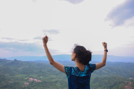 young woman cheering open arms at mountain peakの写真素材