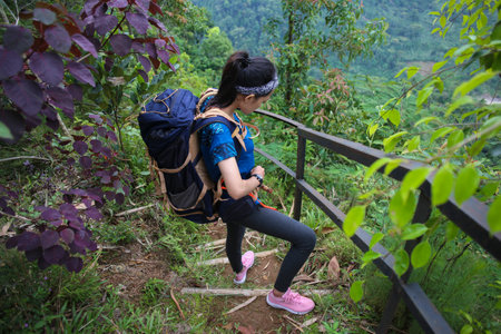young asian woman backpacker climbing mountain
