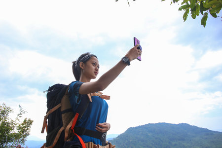 A tourist woman uses a smartphone in the mountainsの写真素材