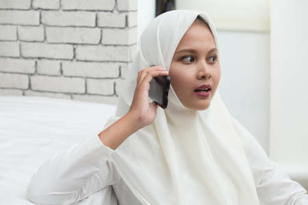 happy young asian muslim woman using mobile phoneの写真素材