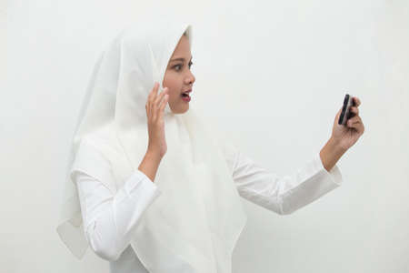 happy young asian muslim woman using mobile phoneの写真素材