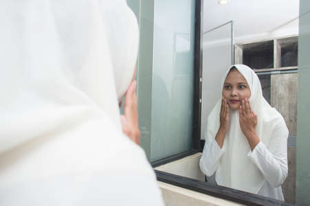 Young asian muslim woman washing face in room.の写真素材