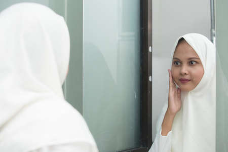 Young asian muslim woman washing face in room.の写真素材