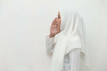 Portrait of young Asian muslim woman wearing hijab shouting and yellingの写真素材