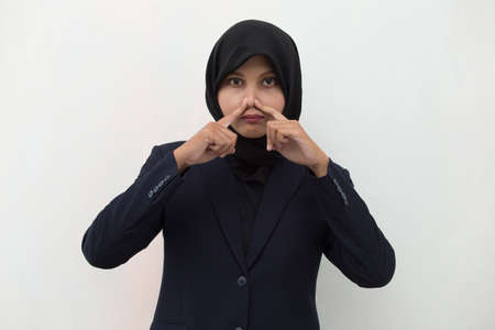 Asian muslim woman holding her nose because of a bad smellの写真素材