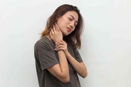 portrait of a beautiful asian young woman with sore throat neck and shoulder pain, isolated on a white backgroundの写真素材