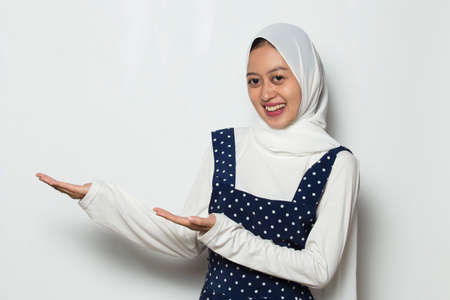 asian muslim woman pointing with fingers to different directions. Copy space for advertisement