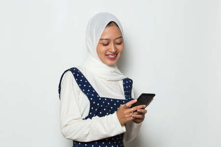 happy young asian muslim woman using mobile phone isolated on white background
