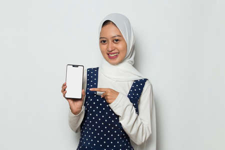 Asian muslim woman in hijab demonstrating mobile cell phone.