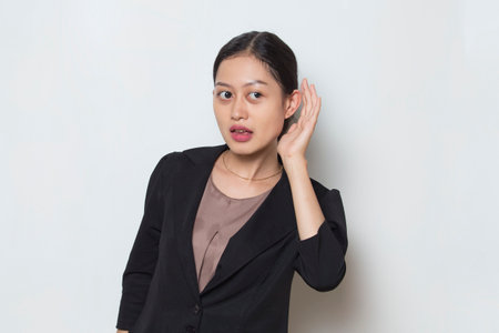 Asian business woman hold her hand near her ear and listeningの写真素材