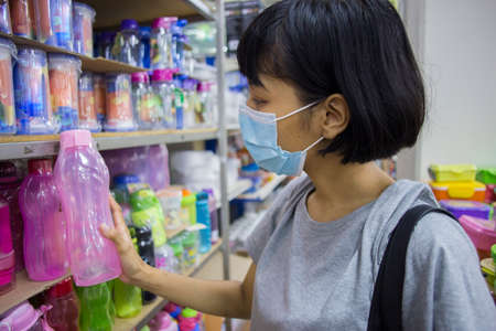 Young asian woman with face mask  buying groceries in the supermarket during virus pandemic