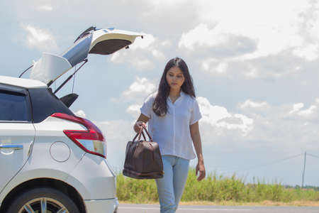 asian woman going to vacations, loading their car boot with travel suitcasesの写真素材