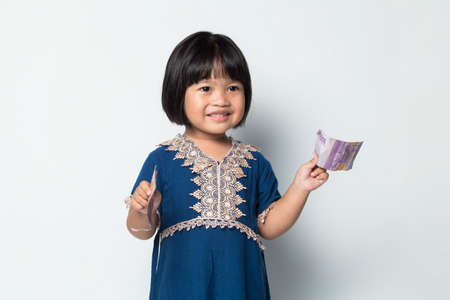 happy little asian girl holding money isolated on white backgroundの写真素材