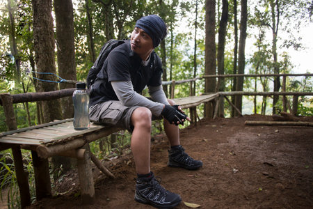 Hiking man relaxing and drinking water from bottle after trekking in the mountainsの写真素材