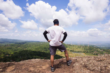 Man hiker with a backpack on top of the mountain back
