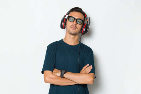 Happy young man listening music dancing and having fun on white backgroundの写真素材