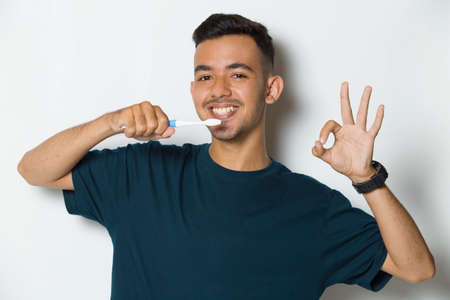 Young handsome man brushing his teeth  isolated on white backgroundの写真素材