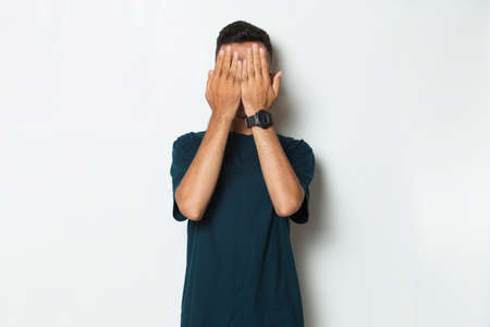 Young handsome man  covers his face with his hands isolated on white backgroundの写真素材