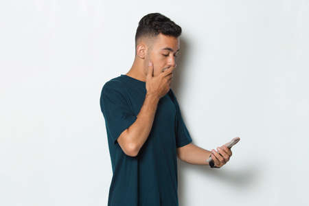shocked  young man using mobile phone isolated on white backgroundの写真素材