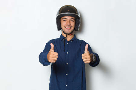 handsome man with a motorcycle helmet showing a thumbs up ok gesture on white backgroundの写真素材