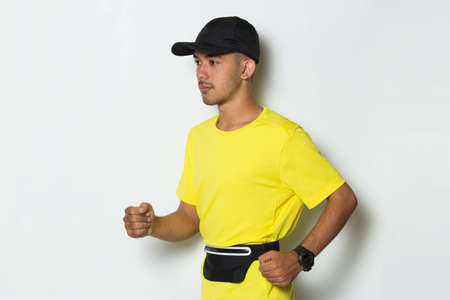 young sporty man dressed in yellow tshirt running on white backgroundの写真素材