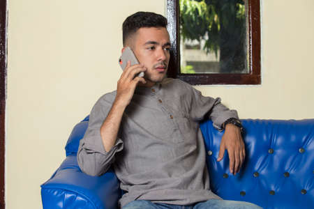 Young handsome man using smatphone when sitting on sofa