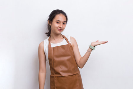 Happy young asian woman barista waitress pointing with fingers to different directions isolated on...