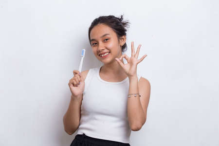 Young beautiful asian woman brushing her teeth isolated on white backgroundの写真素材