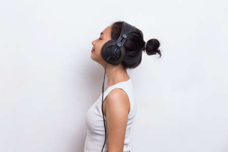 Beautiful young asian woman listening to music isolated on white background