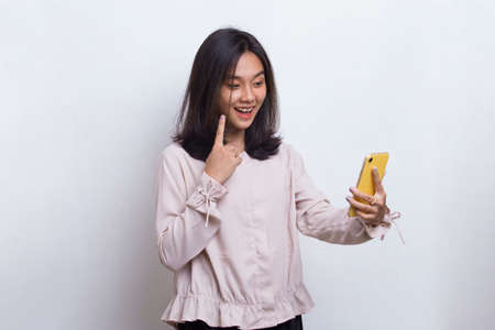 happy young asian beautiful woman using mobile phone isolated on white backgroundの写真素材