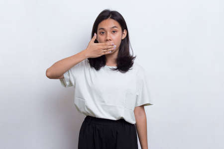 Young asian beautiful woman shocked covering mouth with hands for mistake. Secret concept isolated on white backgroundの写真素材