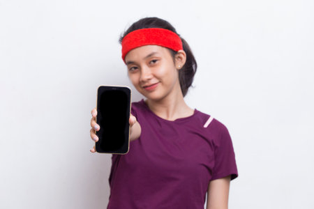 young asian sporty woman demonstrating mobile phone on white backgroundの写真素材