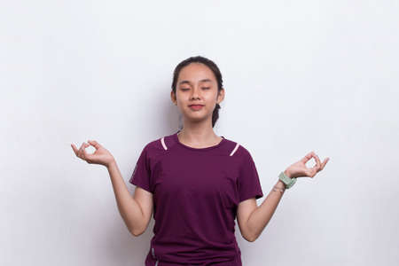 Young beautiful asian sport woman doing yoga relaxing meditating on white backgroundの写真素材