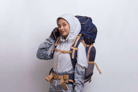 Young beautiful asian hiker woman using mobile phone isolated on white backgroundの写真素材