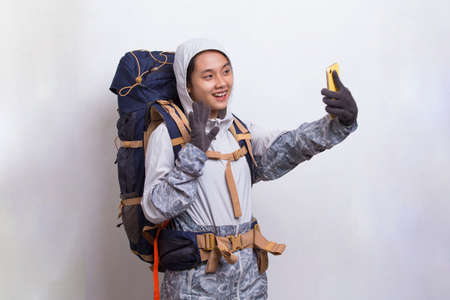Young beautiful asian hiker woman using mobile phone isolated on white backgroundの写真素材