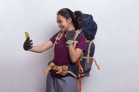 Young beautiful asian hiker woman using mobile phone isolated on white backgroundの写真素材