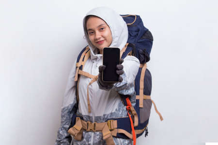 Young asian hiker woman showing mobile phone isolated on white backgroundの写真素材