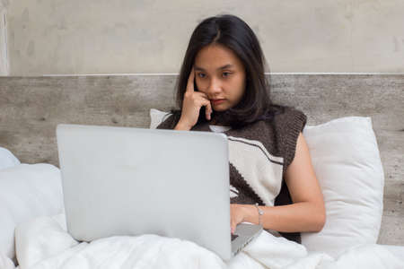 Portrait Asian beautiful young woman using laptop computer in home living room isolated on white backgroundの写真素材