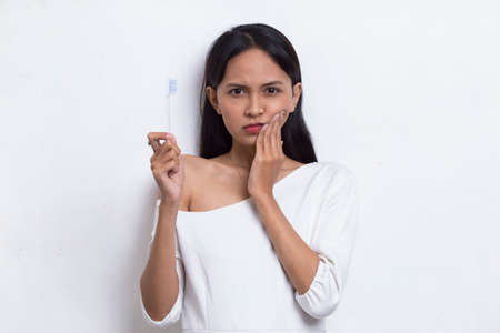 asian beautiful young woman suffering from toothache pain, tooth decay, tooth sensitivity; oral health care, dental care concept on white backgroundの写真素材