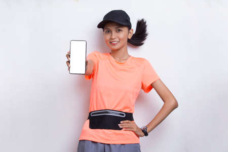 young asian sporty woman demonstrating mobile phone on white background