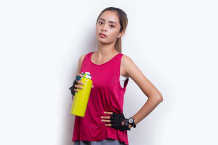 Young beautiful asian sport woman drinking water after workout on white backgroundの写真素材