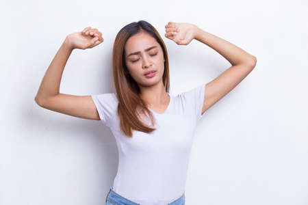 beautiful young asian girl waking up stretching isolated on white backgroundの写真素材