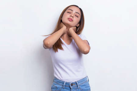 beautiful asian young woman with sore throat neck and shoulder pain isolated on a white backgroundの写真素材