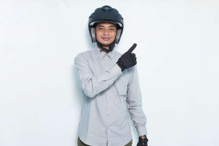 handsome asian man with a motorcycle helmet pointing with fingers to different directions isolated on white background