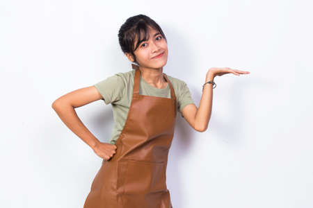 Happy young asian woman barista waitress pointing with fingers to different directions isolated on...