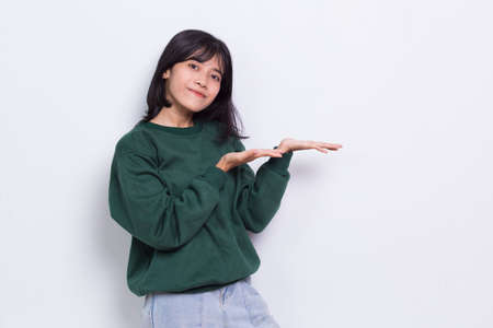 Happy young asian woman pointing with fingers to different directions isolated on white backgroundの写真素材