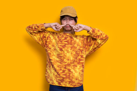 young asian beautiful woman holding her nose because of a bad smelling something isolated on yellow backgroundの写真素材